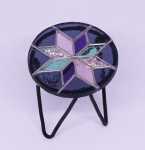 Miniature black stained glass mosaic table of star in gold black and brown, black wire legs, 2 ⅛” x 1 ¾” x 1 ¾” 