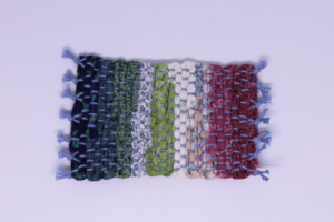 Miniature red, white, green, and blue handwoven cotton rag with blue fringe, 3” x 5 ½”