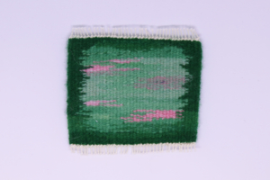Miniature green and pink handwoven rug with white fringe
