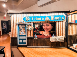 Person peek through window of miniature bookstore scene